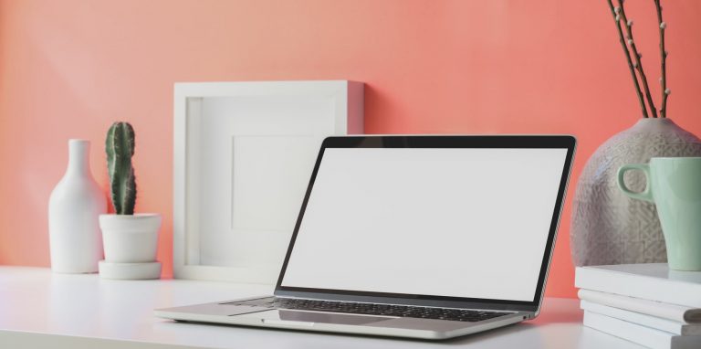 laptop beside peach color wall